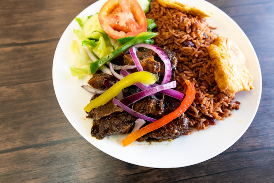 Plated dish with rice, vegetables, and meat on a wooden surface